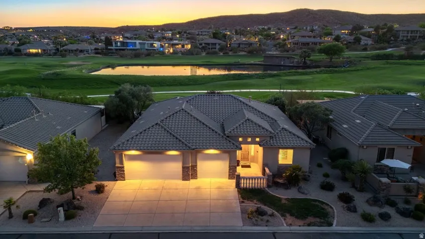 View of front facade featuring a water and mountain view, a residential view, a tiled roof, view of golf course, and a garage