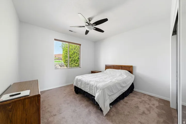 Carpeted bedroom featuring ceiling fan and baseboards