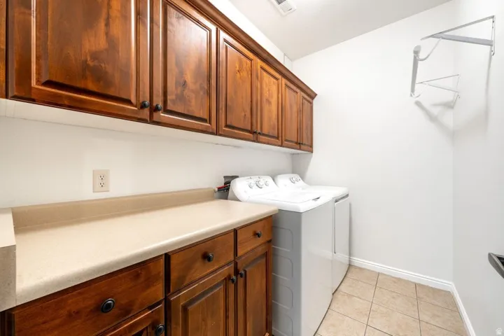 Laundry room with cabinet space, light tile patterned flooring, and separate washer and dryer