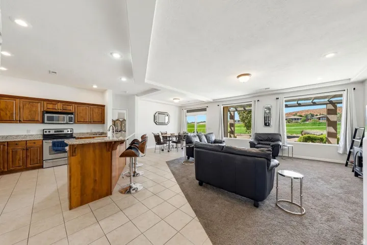 Kitchen featuring a kitchen bar, open floor plan, recessed lighting, stainless steel appliances, and light stone countertops