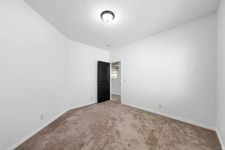 Carpeted spare room featuring baseboards