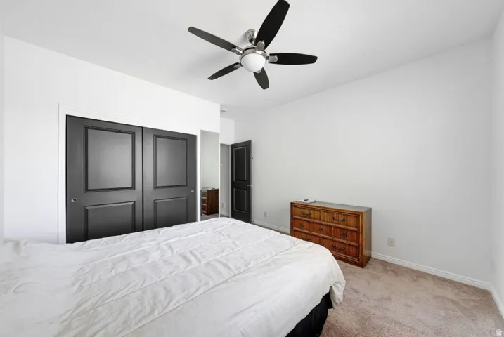 Bedroom featuring light colored carpet, ceiling fan, and a closet