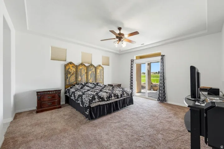 Bedroom featuring access to exterior, carpet flooring, a ceiling fan, and a raised ceiling