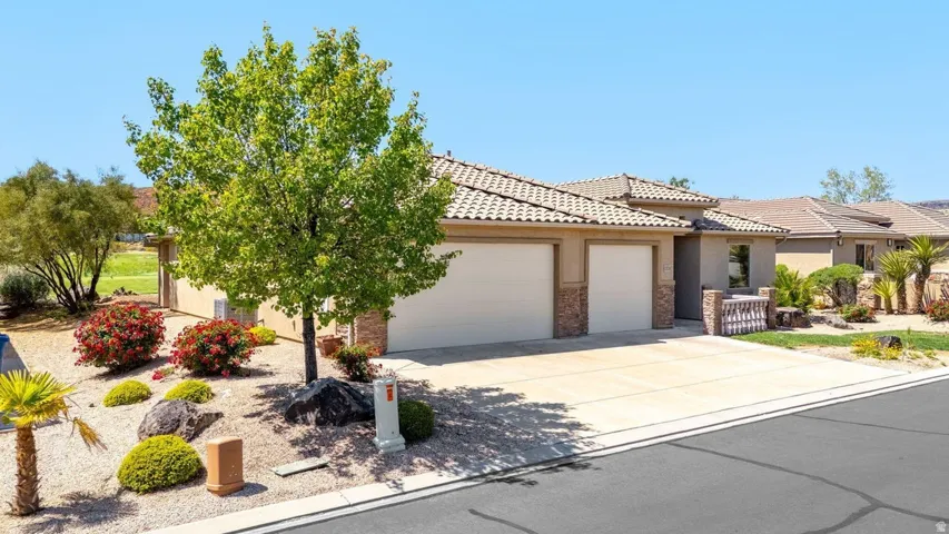 View of front of property featuring an attached garage, driveway, stucco siding, and a tiled roof
