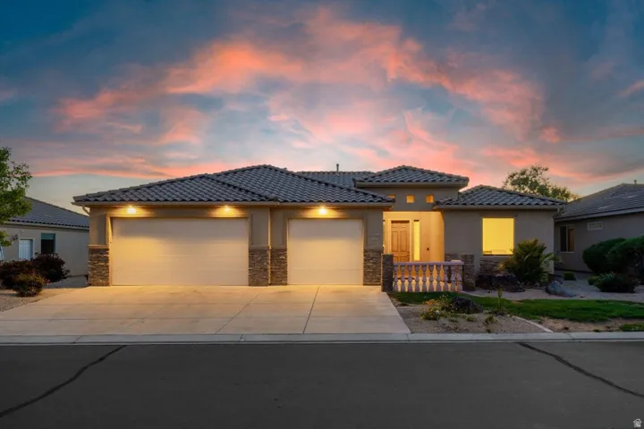 View of front of house featuring stone siding, an attached garage, driveway, and a tiled roof