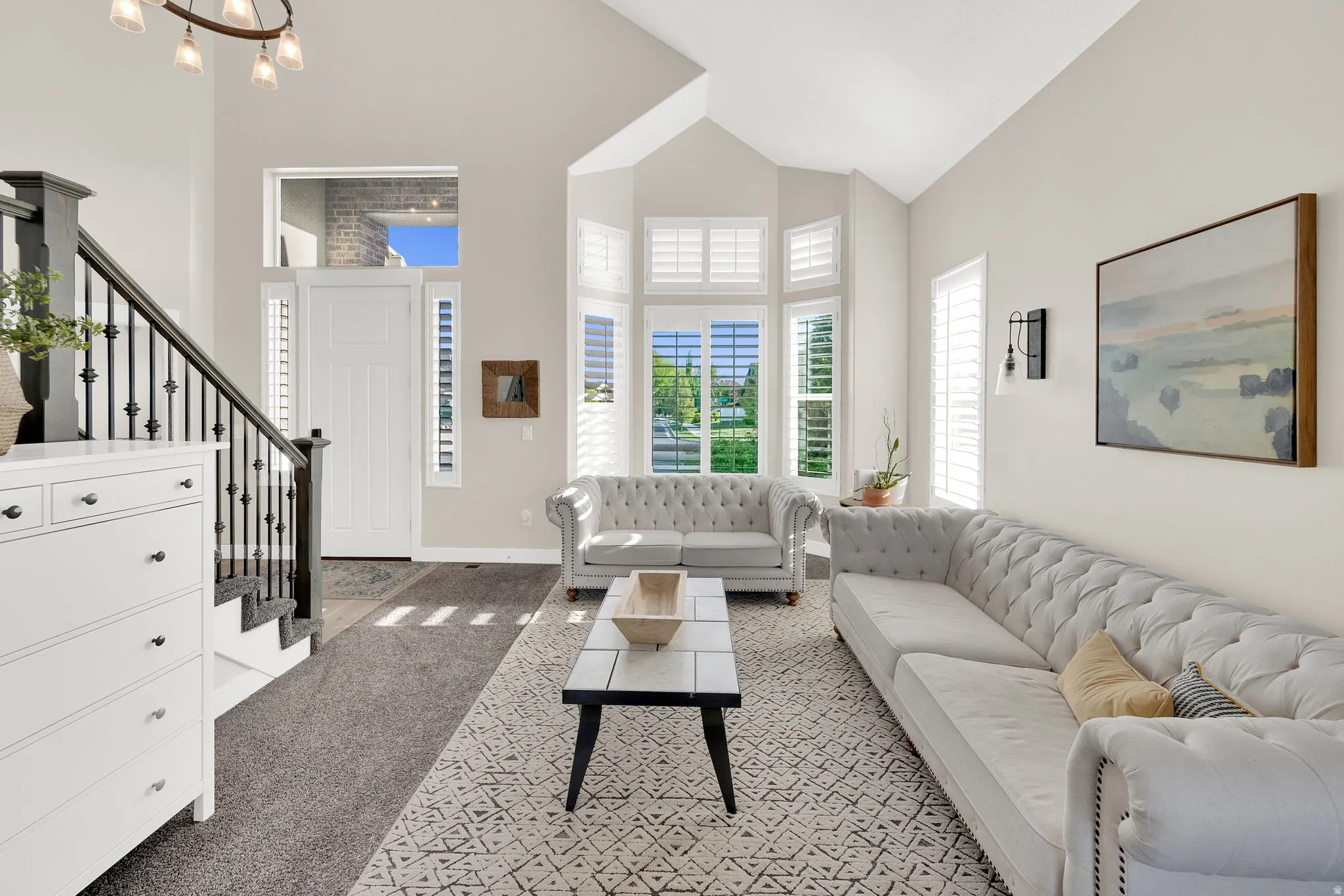 Living area featuring light carpet, lofted ceiling, and suspended lighting