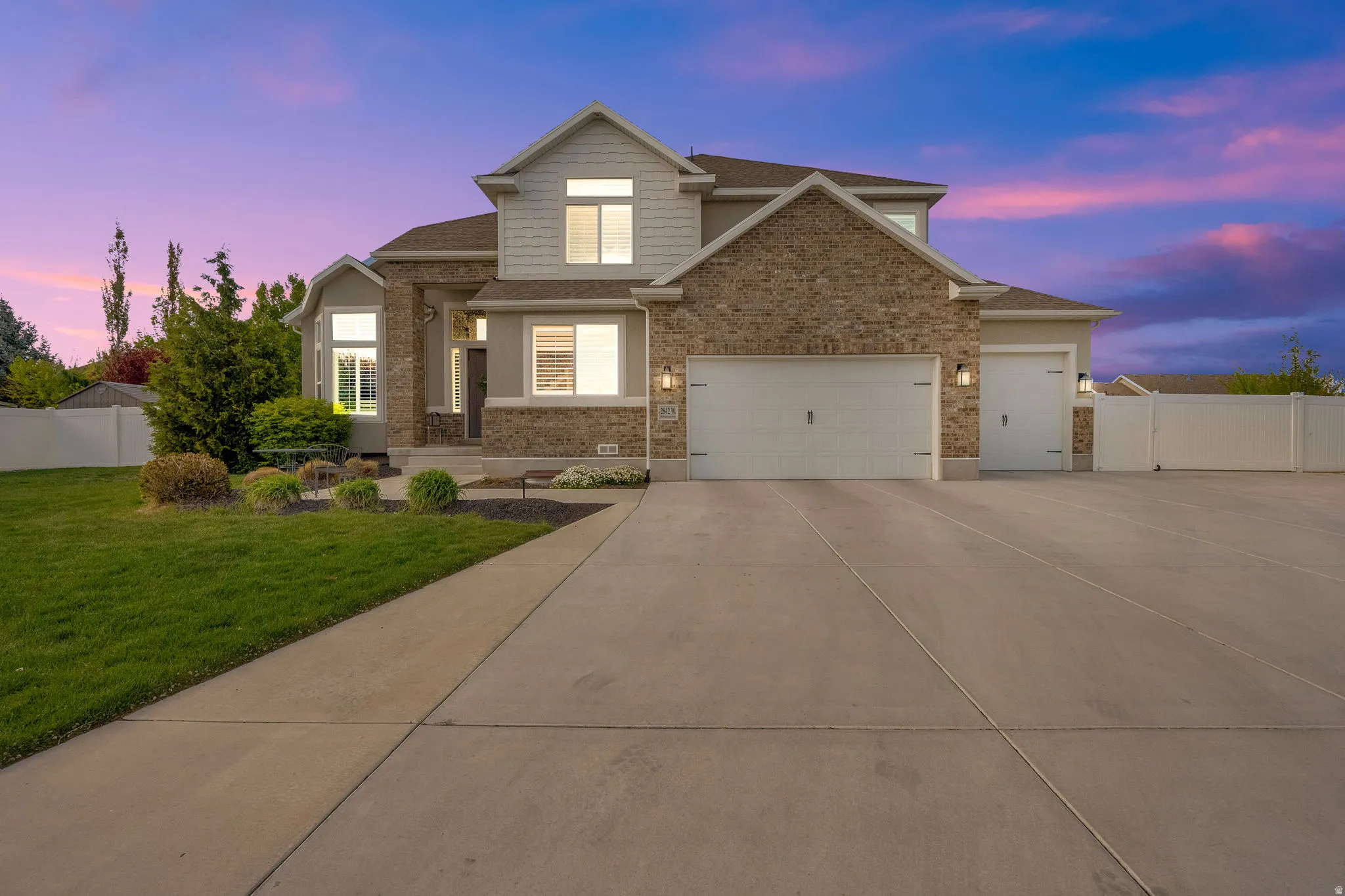View of front of house featuring concrete driveway, an attached garage, brick siding, roof with shingles, and a gate