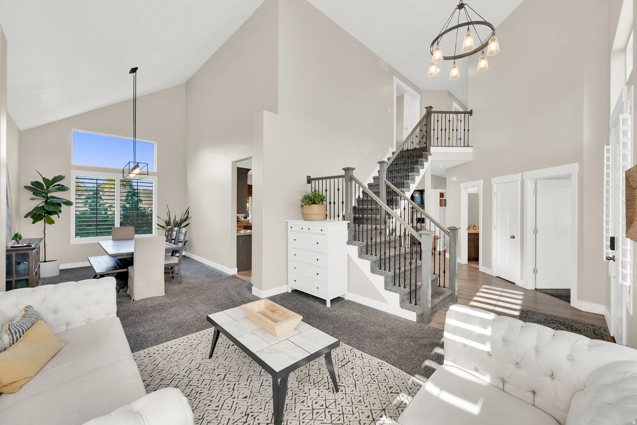 Living room with suspended lighting, carpet floors, and vaulted ceiling
