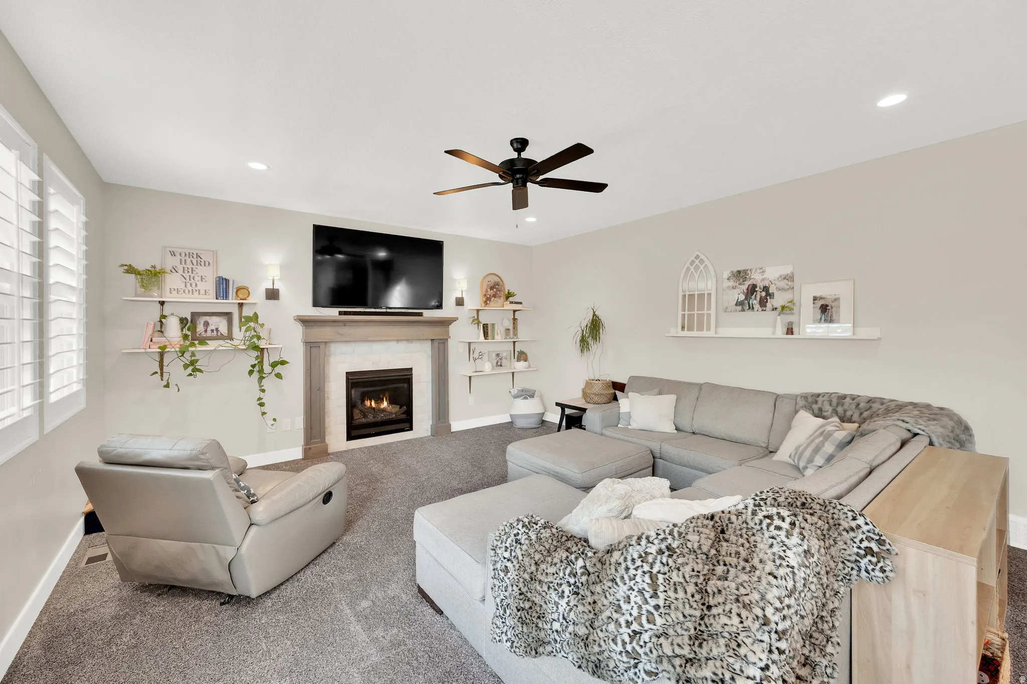 Carpeted living room with a tile fireplace, ceiling fan, and recessed lighting