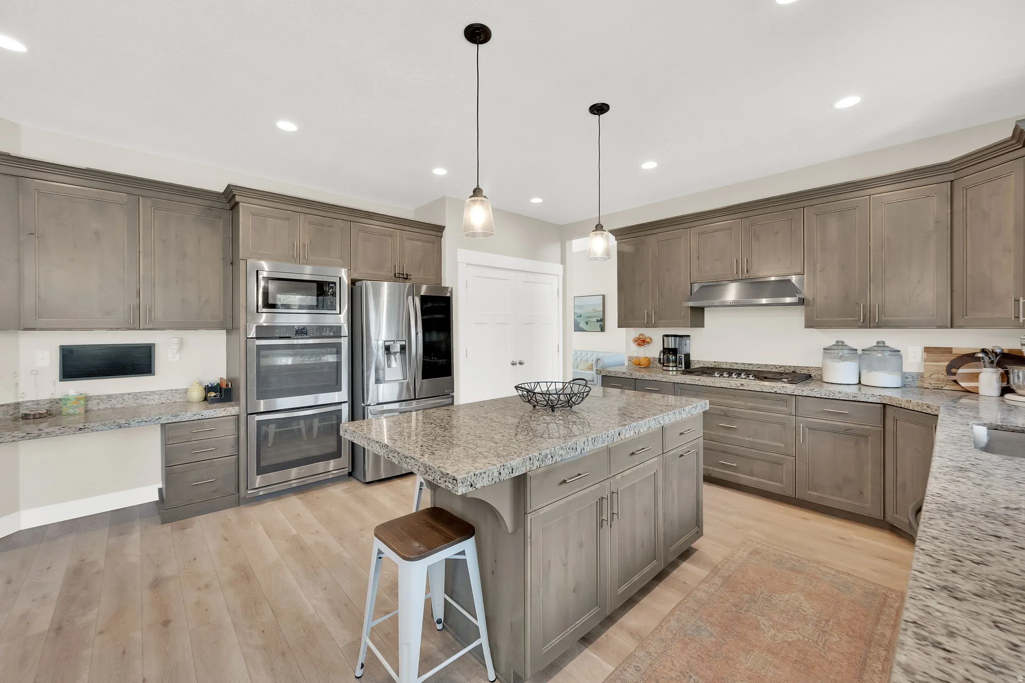 Kitchen with stainless steel appliances, a breakfast bar area, light wood finished floors, and hanging light fixtures