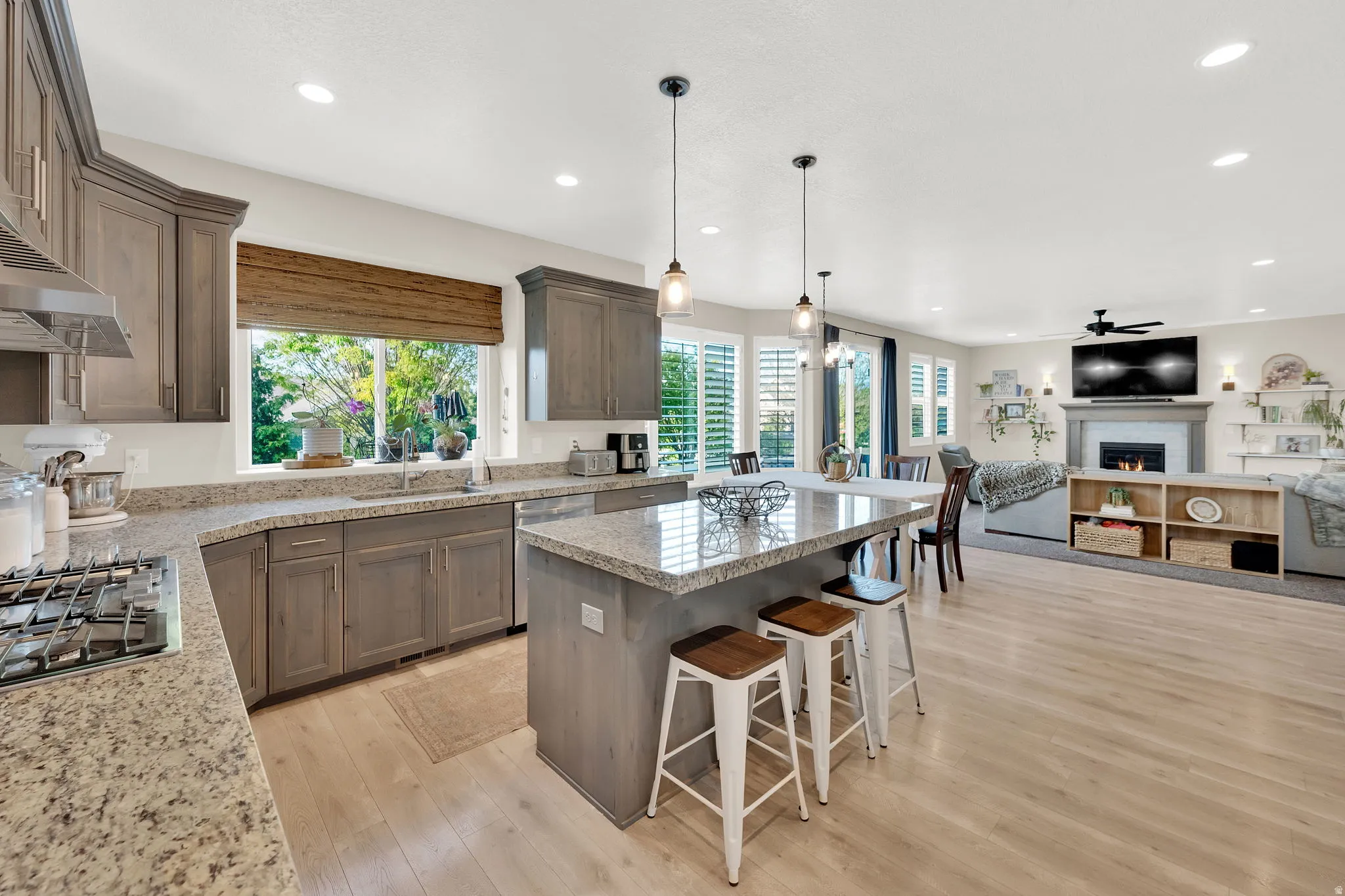 Kitchen with a breakfast bar area, open floor plan, a kitchen island, a warm lit fireplace, and healthy amount of natural light