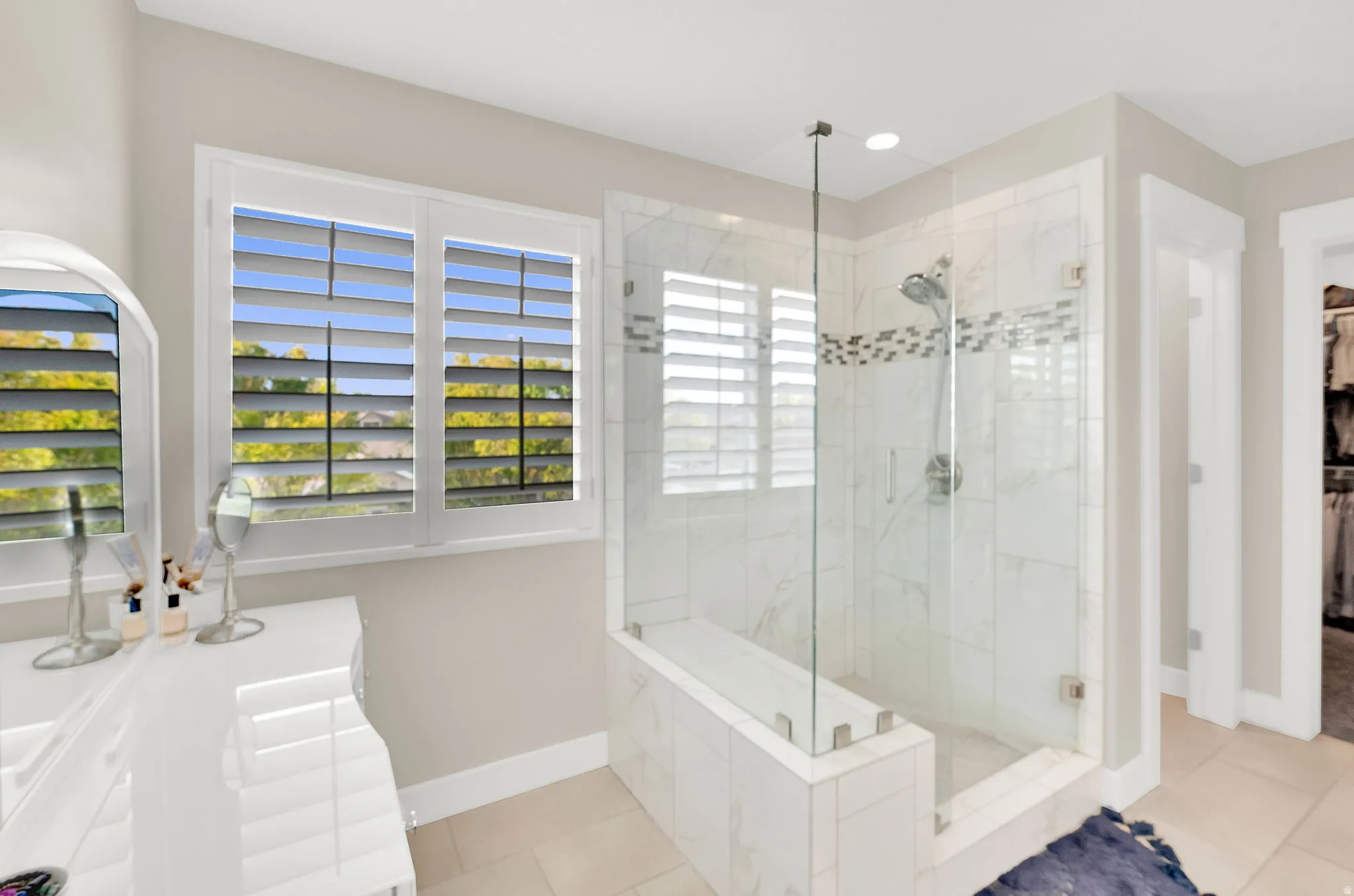 Full bath featuring a marble finish shower, a spacious closet, light tile patterned floors, vanity, and recessed lighting