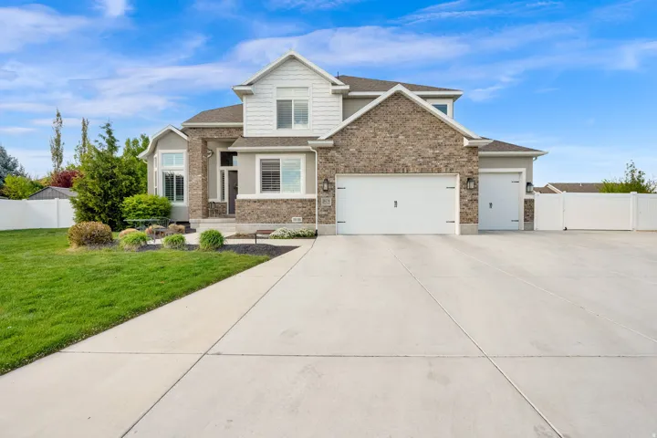 View of front of house featuring an attached garage, driveway, roof with shingles, brick siding, and a gate