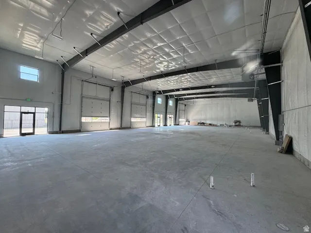 Misc room with a garage, plenty of natural light, a high ceiling, and heating unit