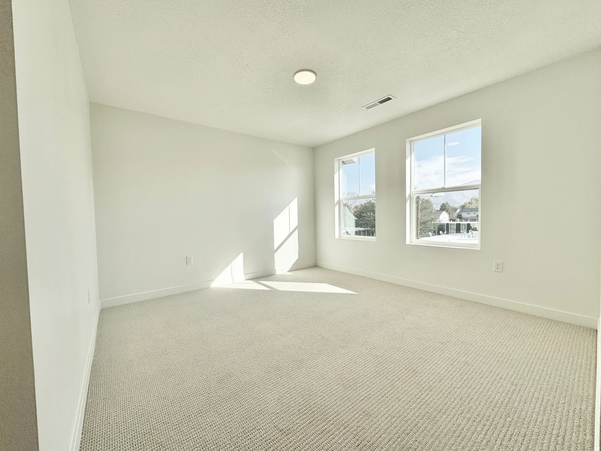 Spare room featuring light colored carpet and a textured ceiling