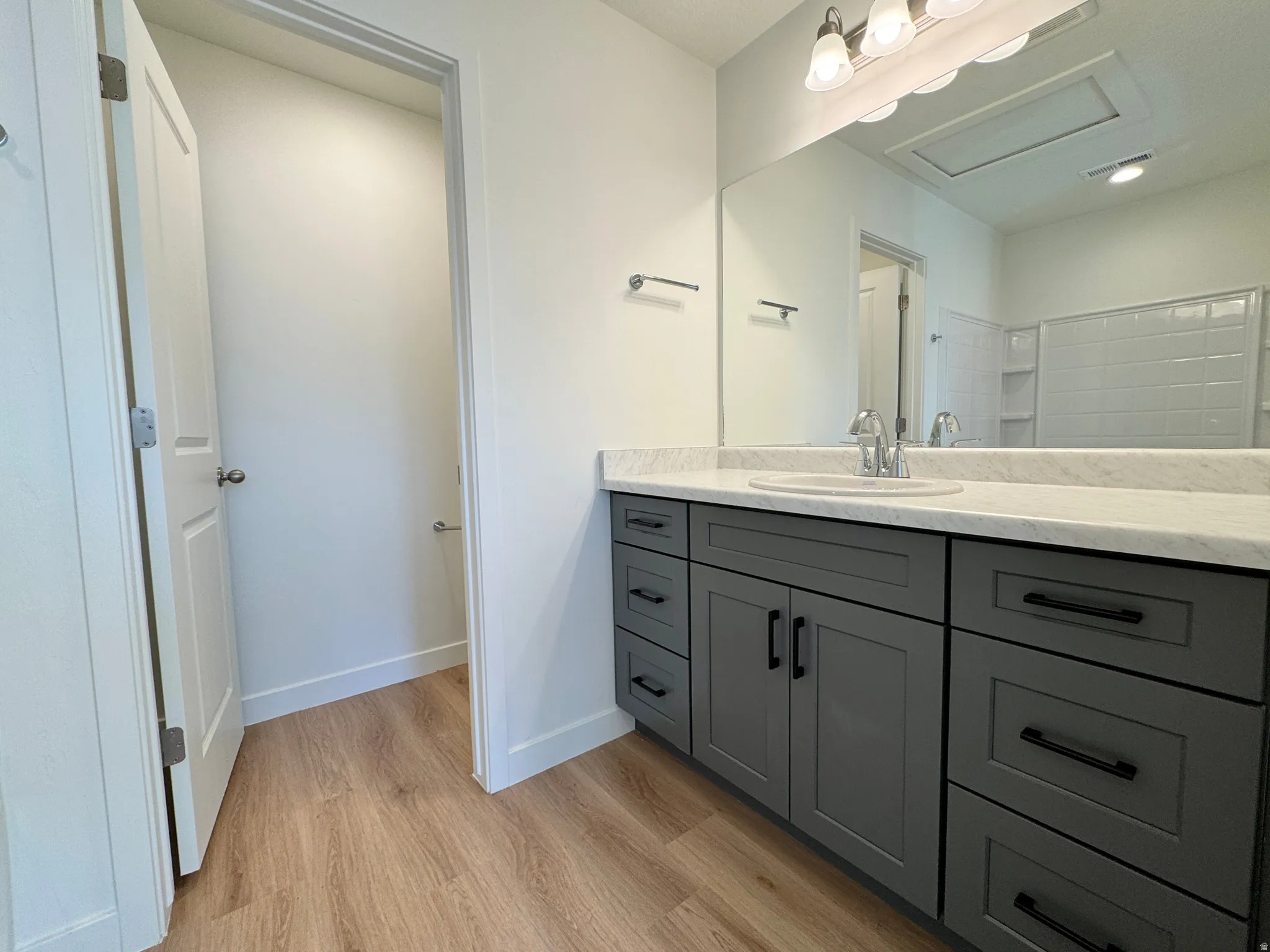 Full bath with vanity and light wood finished floors