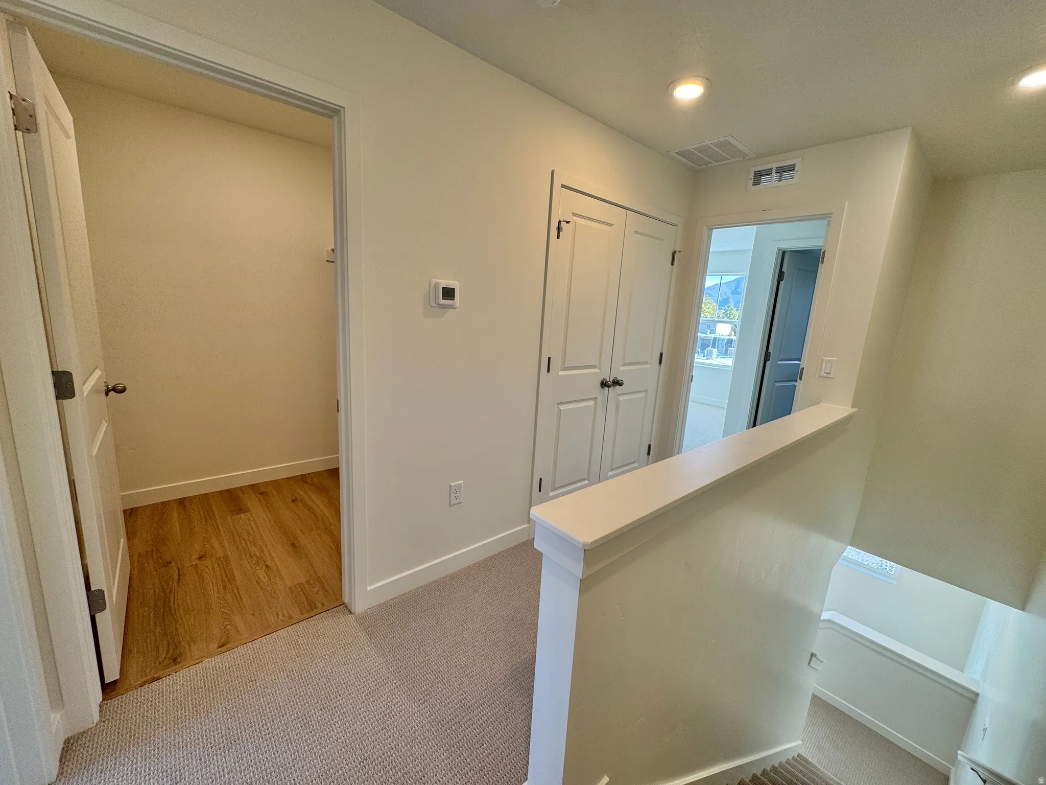 Hallway featuring an upstairs landing, light colored carpet, and recessed lighting