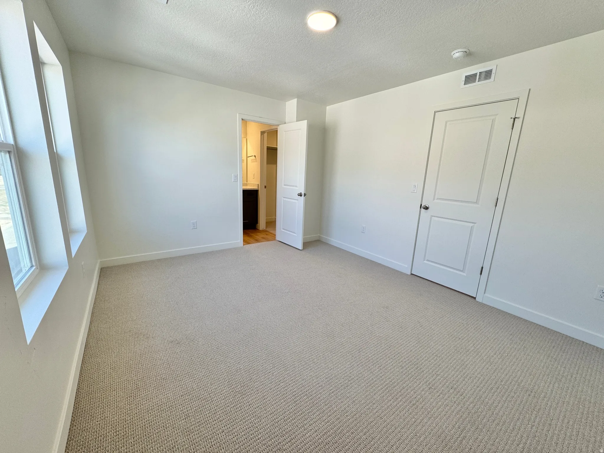 Unfurnished bedroom with light colored carpet and a textured ceiling