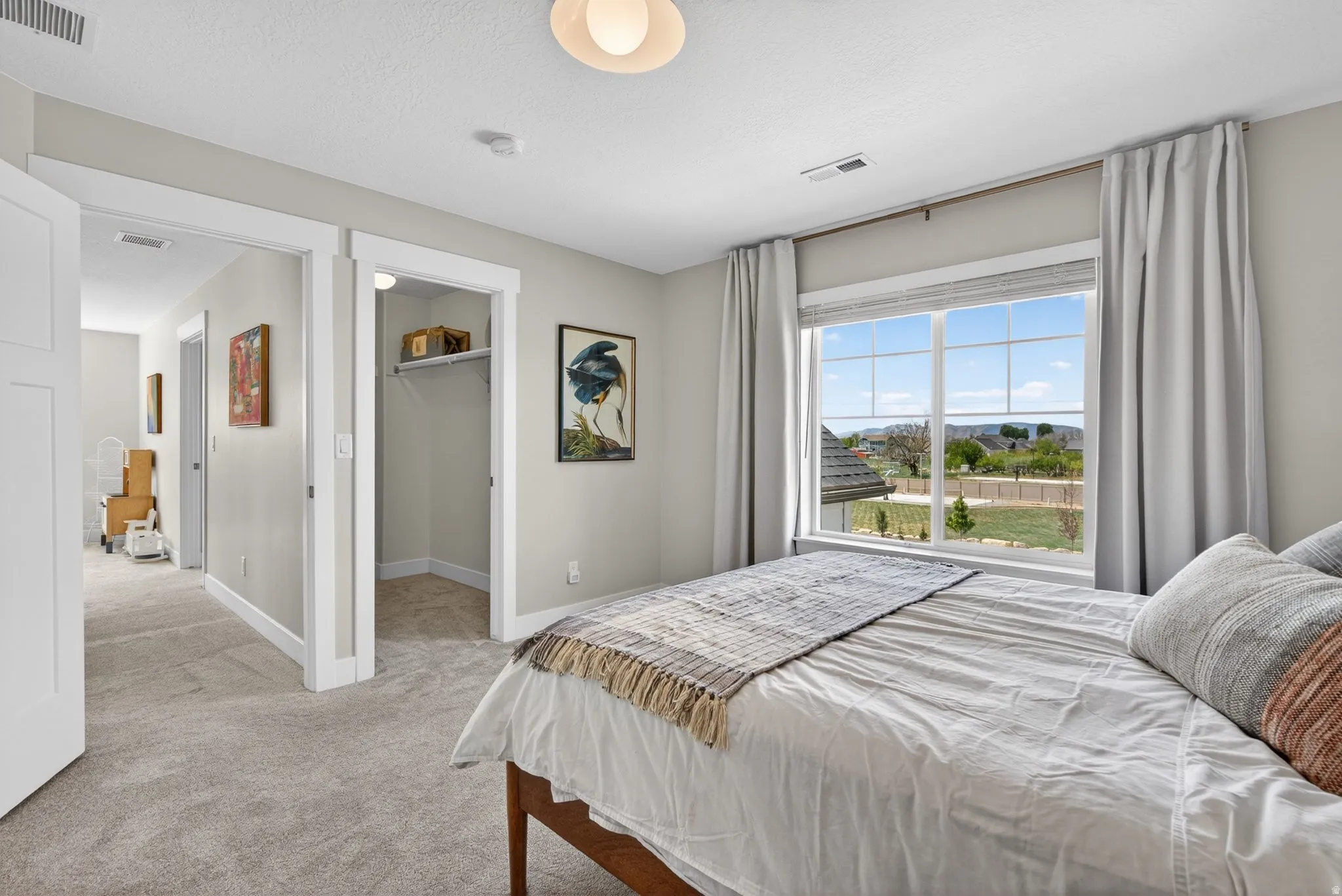 Bedroom with a spacious closet, light carpet, and a textured ceiling