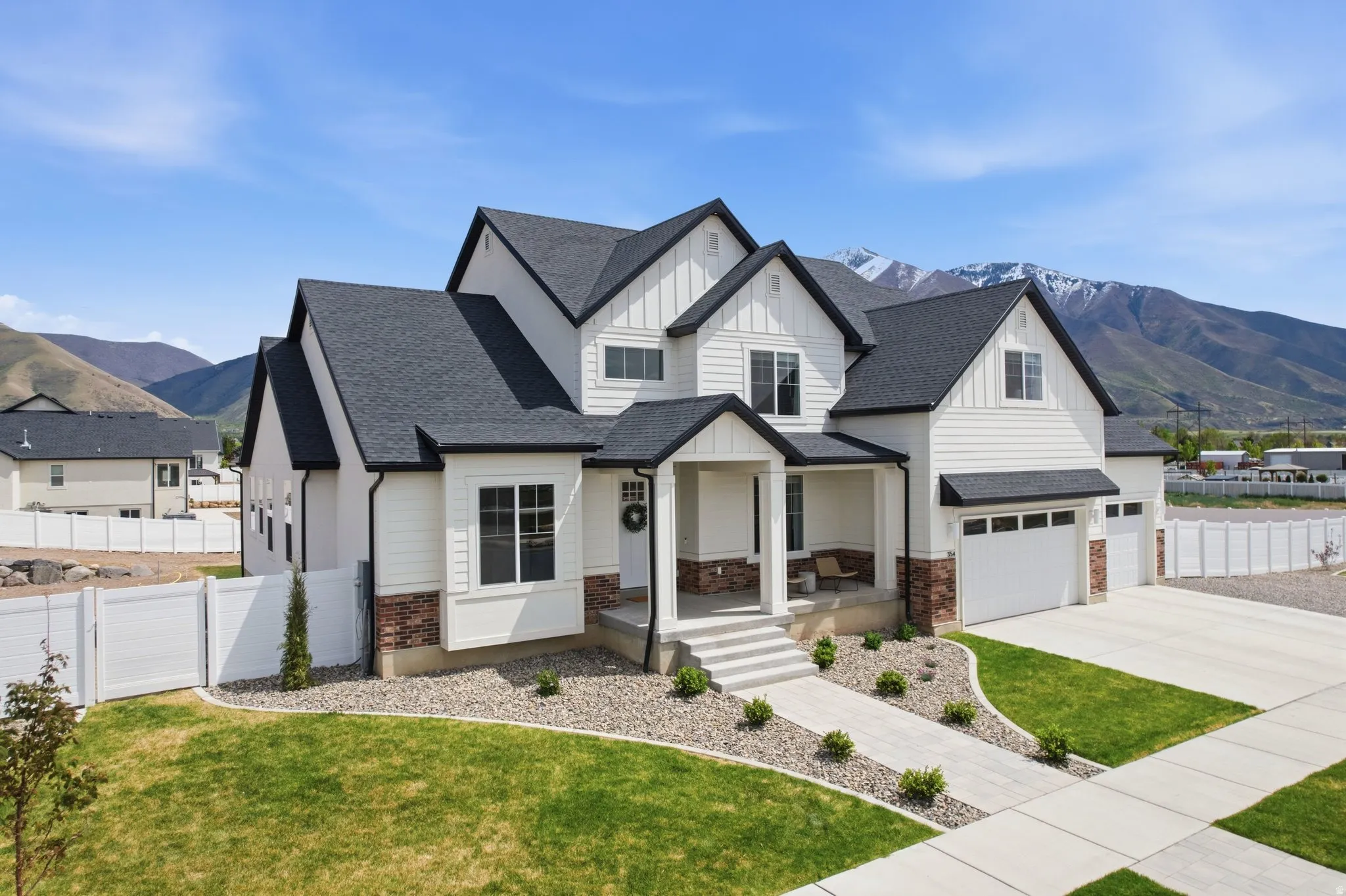 Modern inspired farmhouse featuring board and batten siding, a mountain view, a porch, a shingled roof, and driveway