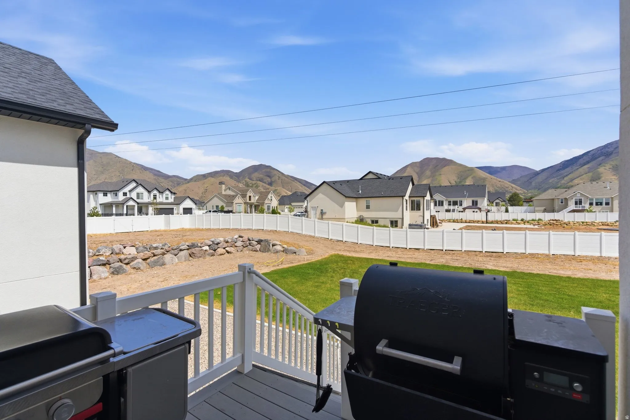 Wooden deck featuring a fenced backyard, area for grilling, a residential view, and a mountain view