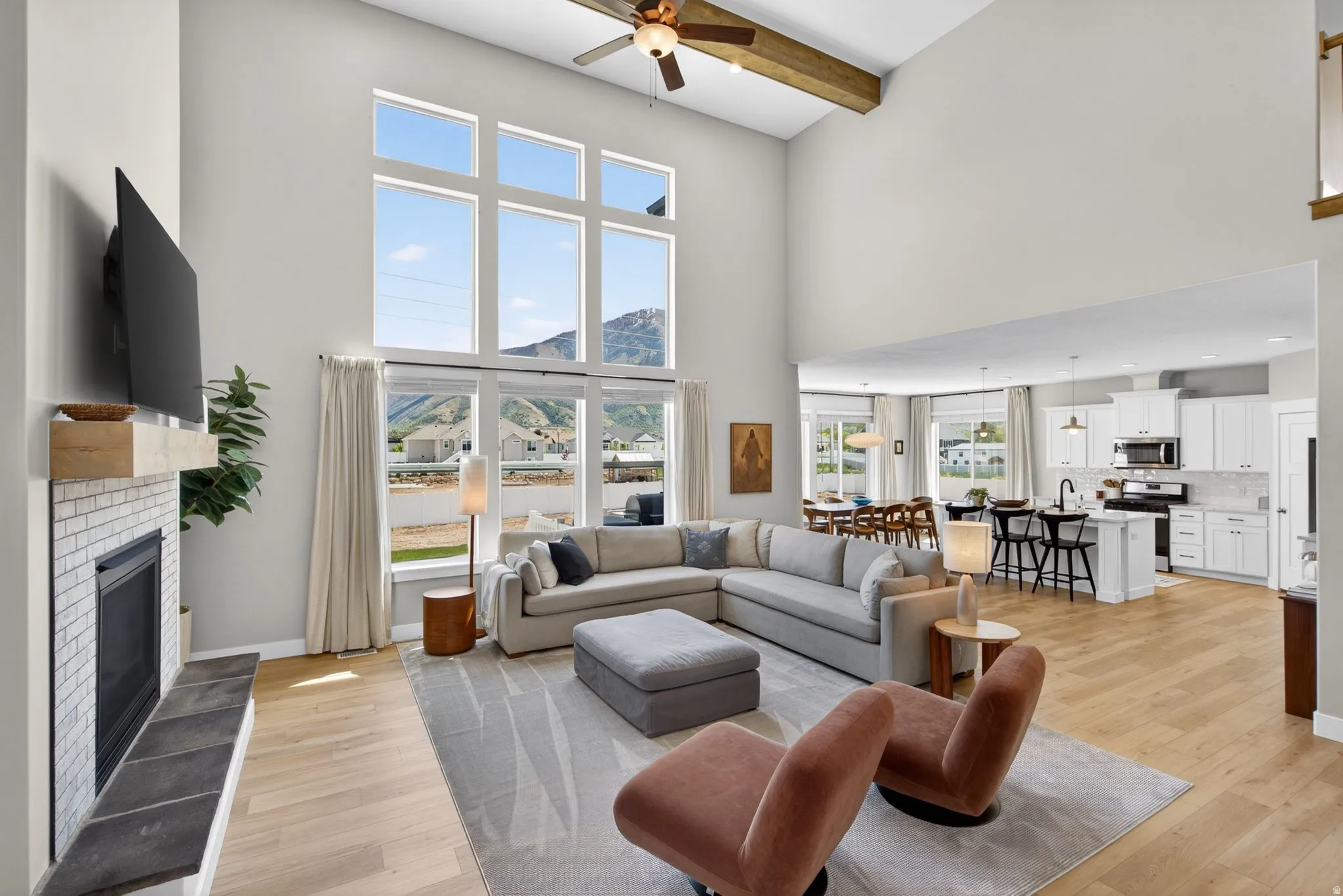 Living area featuring a mountain view, light wood-style flooring, ceiling fan, and a glass covered fireplace