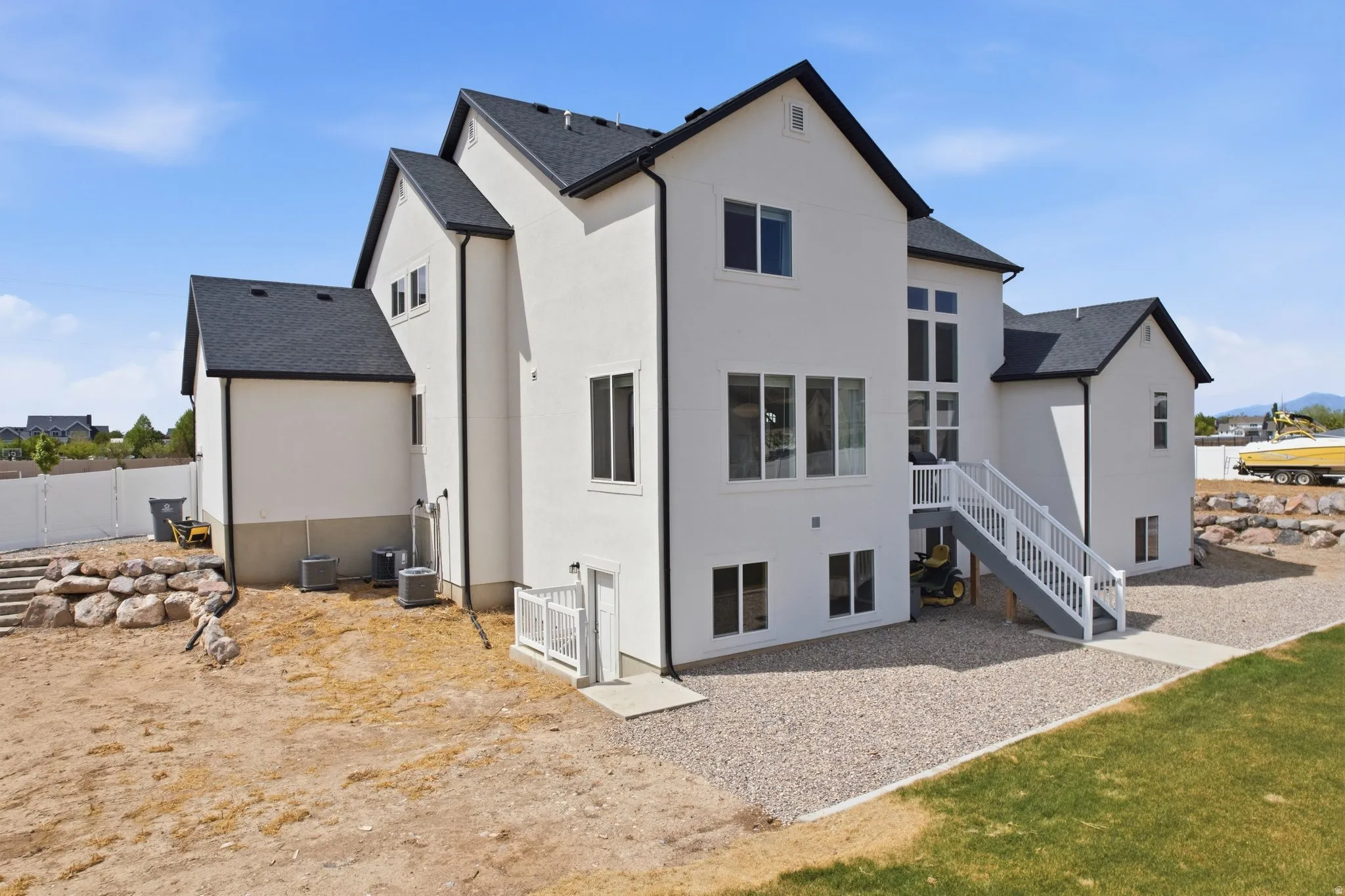 Rear view of house featuring stucco siding and roof with shingles