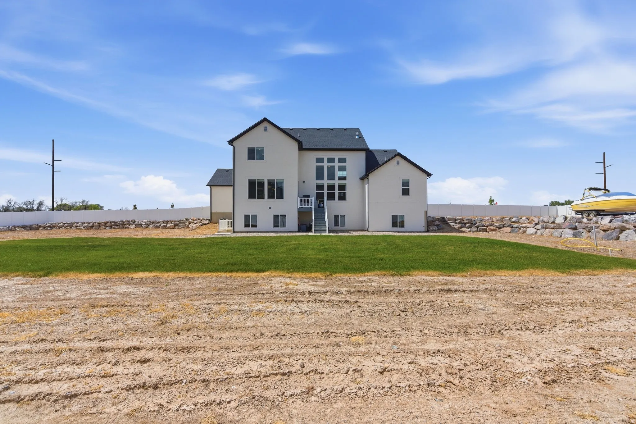 Rear view of house with stucco siding, a lawn, and a patio