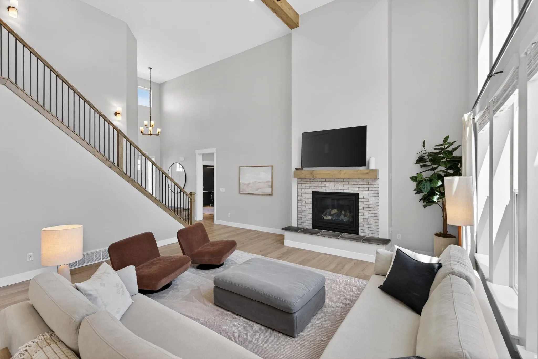 Living room featuring a brick fireplace, wood finished floors, and hanging lights