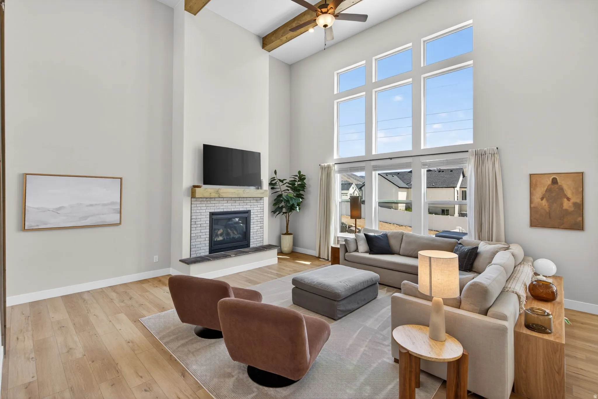 Living area with a ceiling fan, light wood finished floors, and a tile fireplace