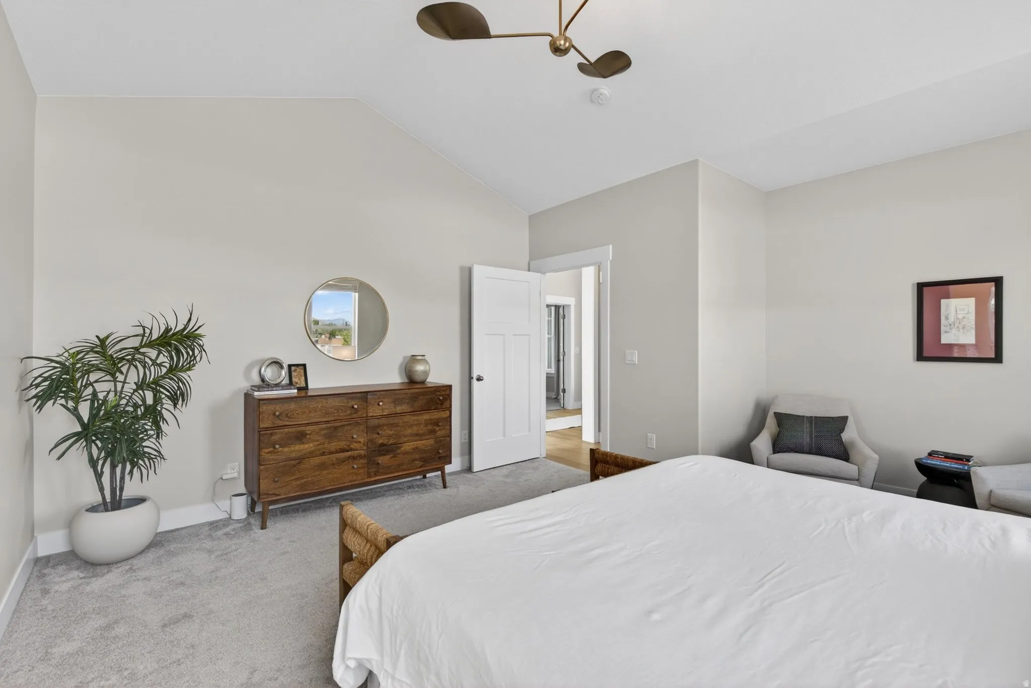 Carpeted bedroom featuring vaulted ceiling and a ceiling fan