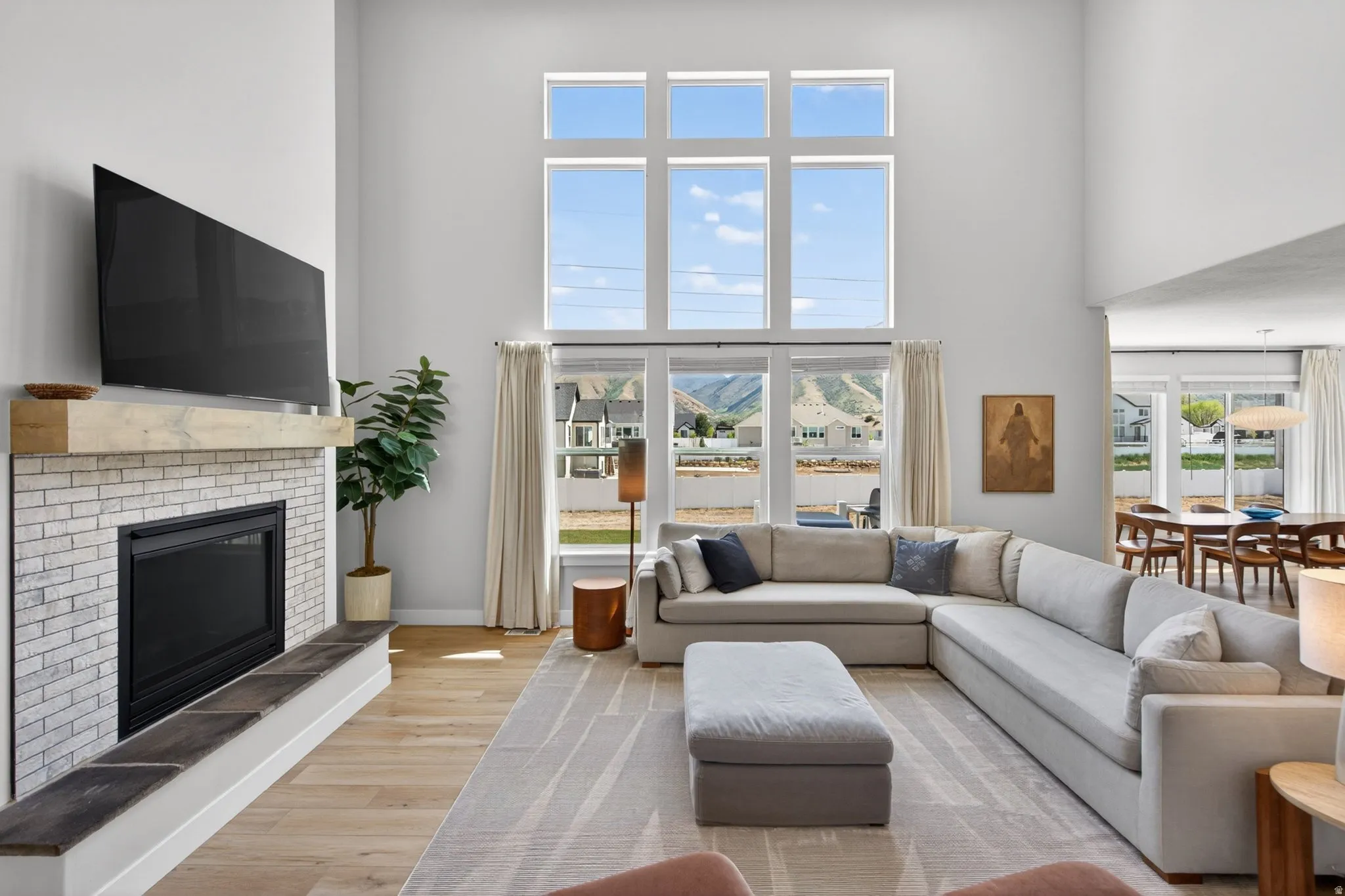 Living area with light wood-style flooring, a fireplace, and a high ceiling