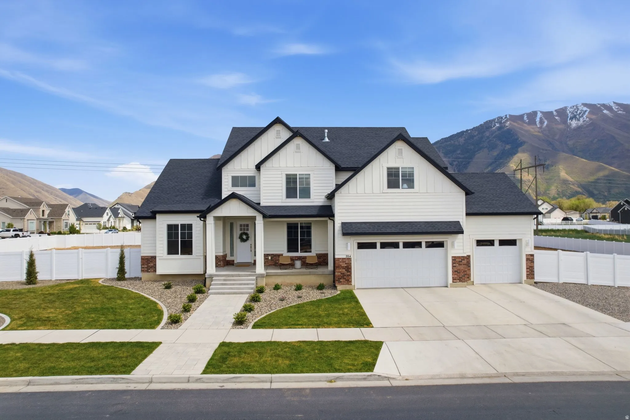 Modern inspired farmhouse with board and batten siding, a porch, a mountain view, a shingled roof, and concrete driveway