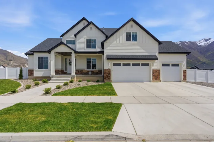 Front View of front facade with a mountain view, a porch, board and batten siding, and concrete driveway
