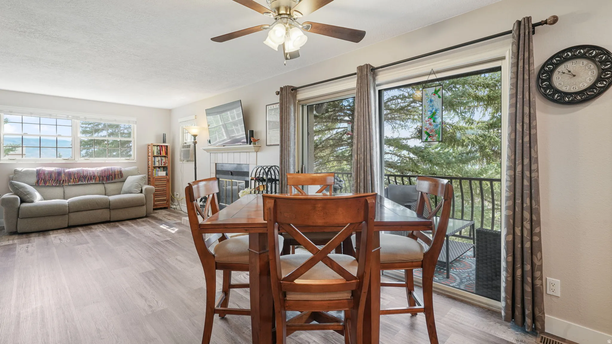 Dining space with a fireplace, wood finished floors, a ceiling fan, and a textured ceiling