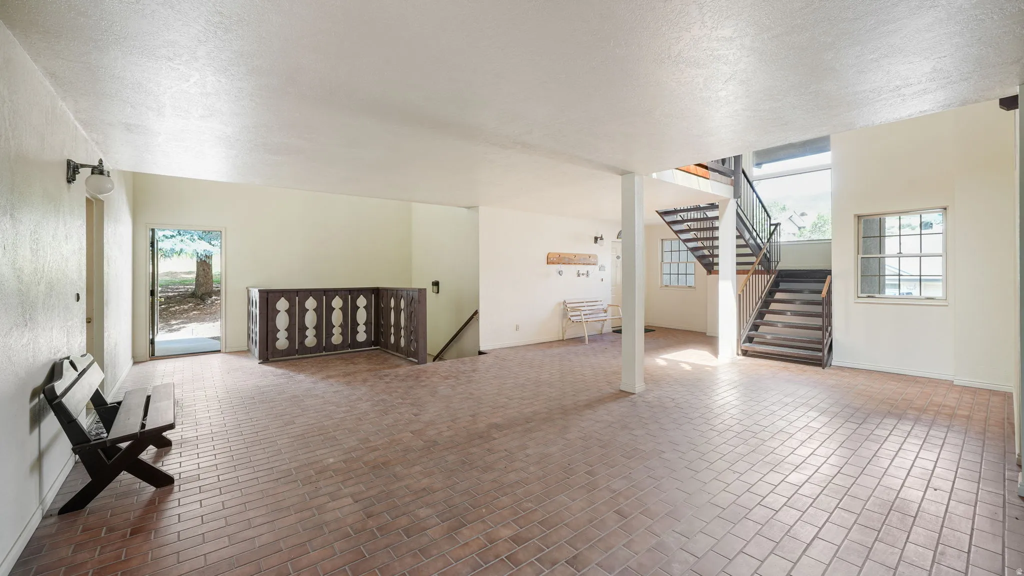 Additional living space with a textured ceiling and brick patterned floors