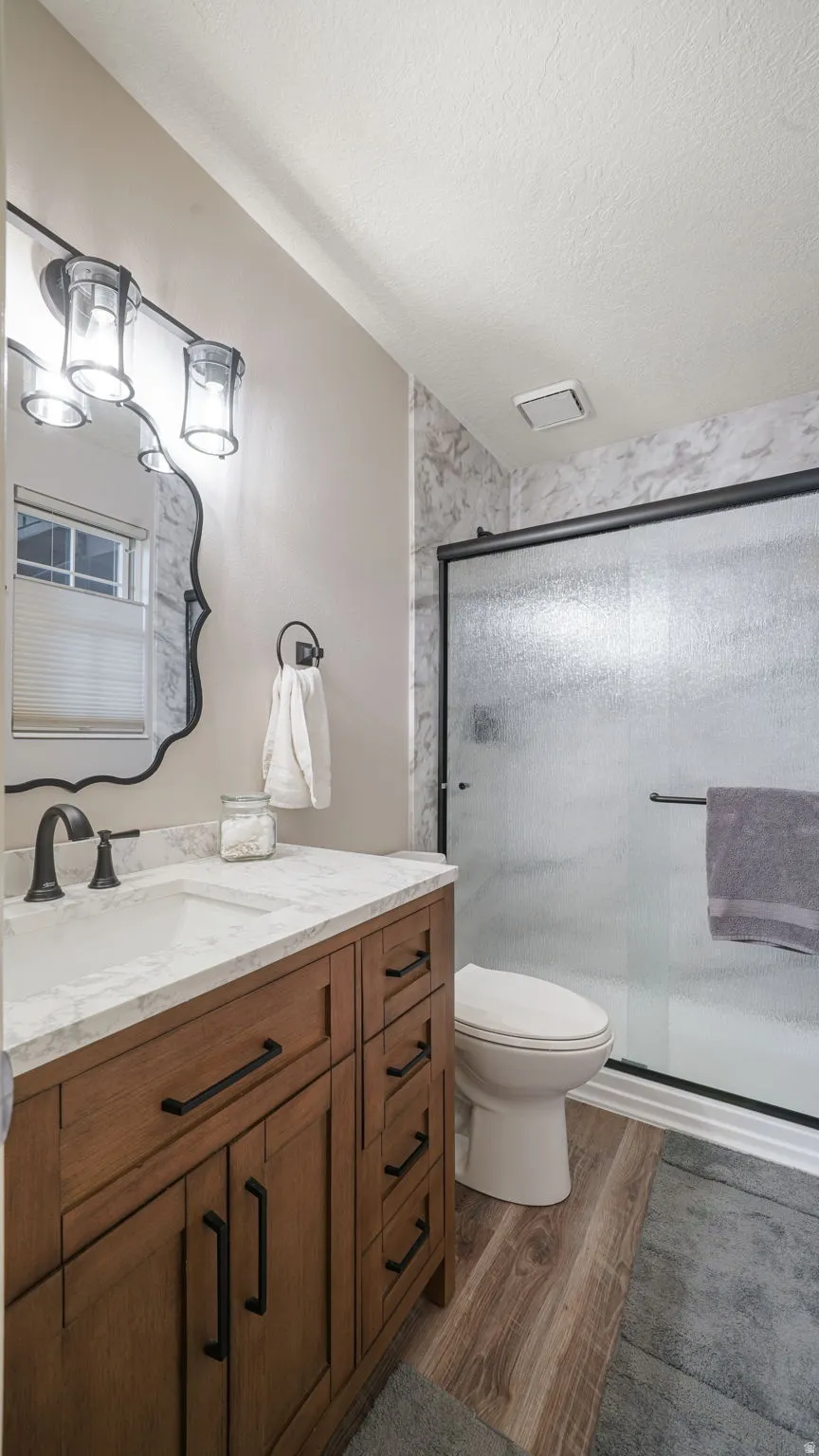 Bathroom featuring a stall shower, vanity, dark wood-style flooring, and a textured ceiling