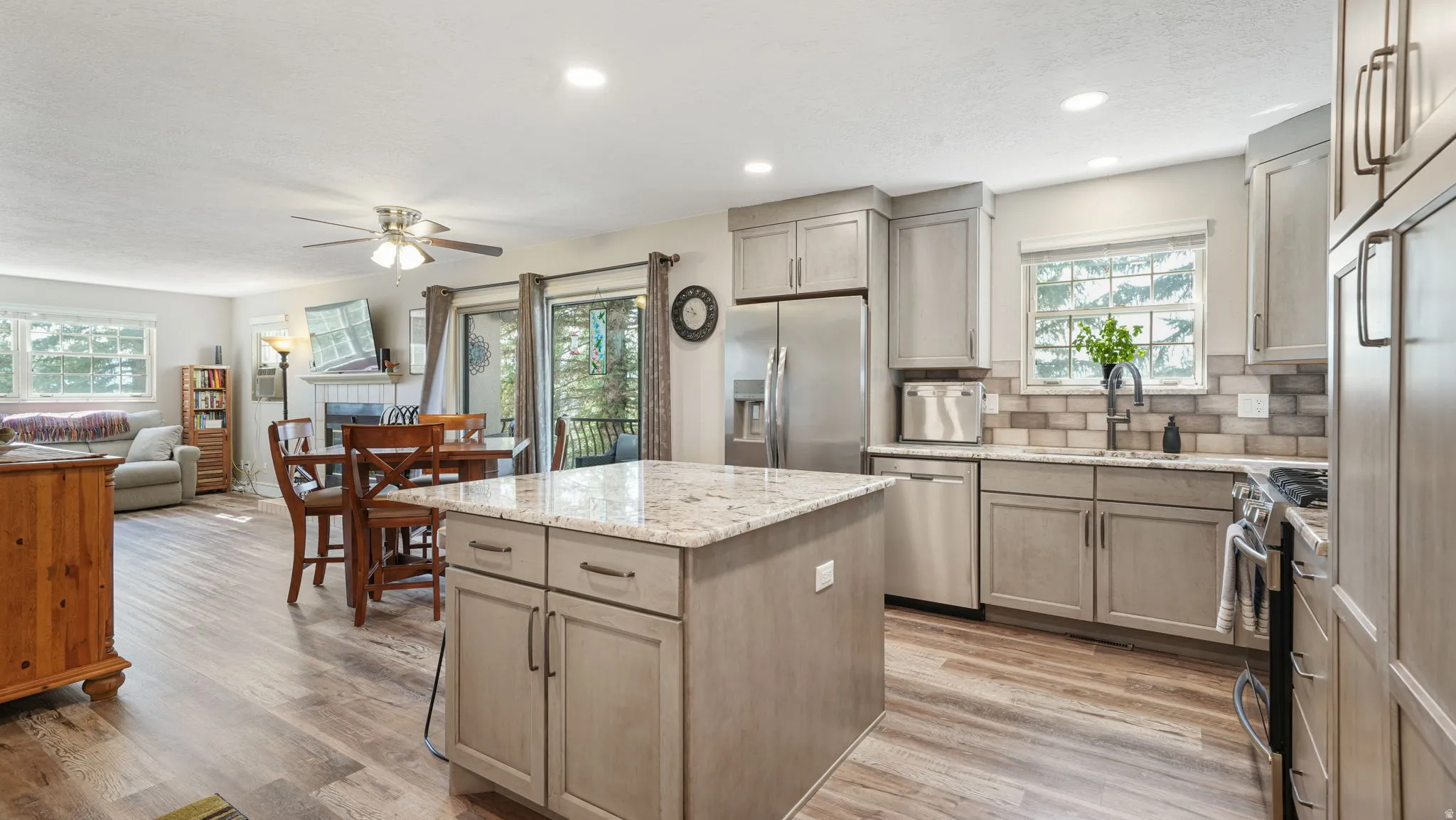 Kitchen with stainless steel appliances, a center island, light stone counters, tasteful backsplash, and light wood-style flooring