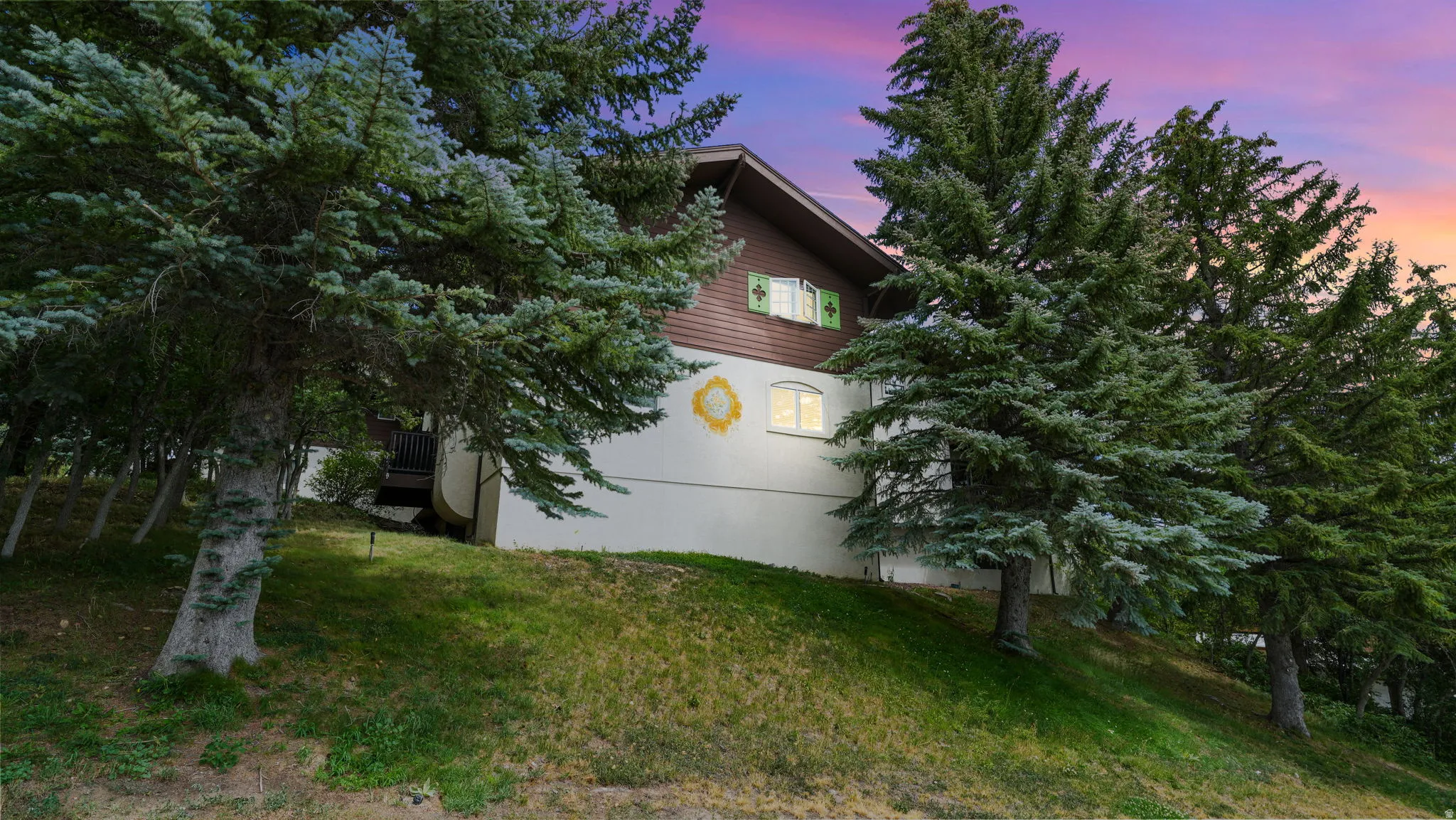 Property exterior at dusk featuring a deck and a lawn