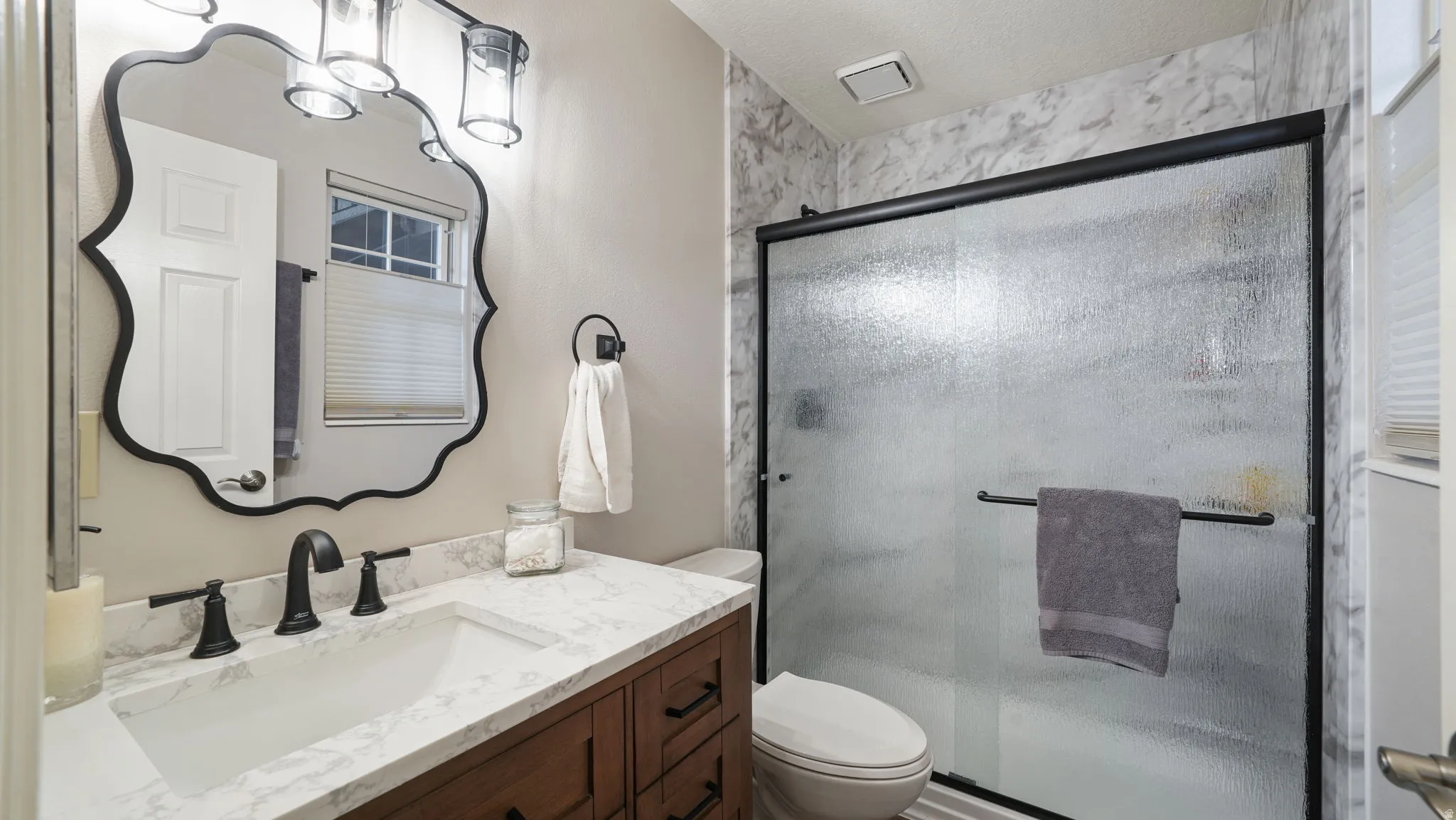 Bathroom featuring vanity, a shower stall, and a textured ceiling