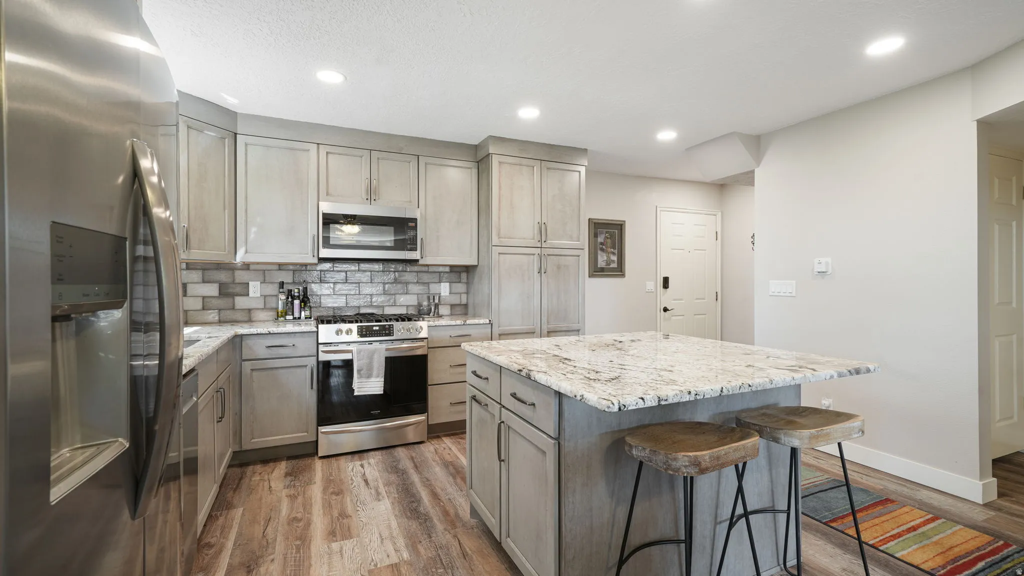 Kitchen with stainless steel appliances, light stone countertops, a center island, a breakfast bar area, and recessed lighting