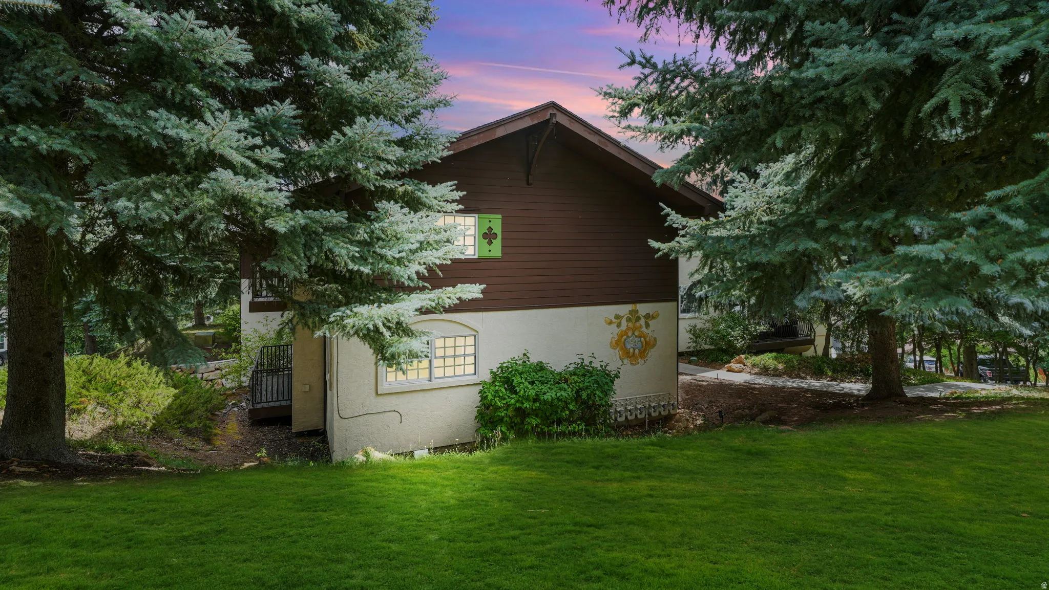 Property exterior at dusk featuring a lawn and stucco siding