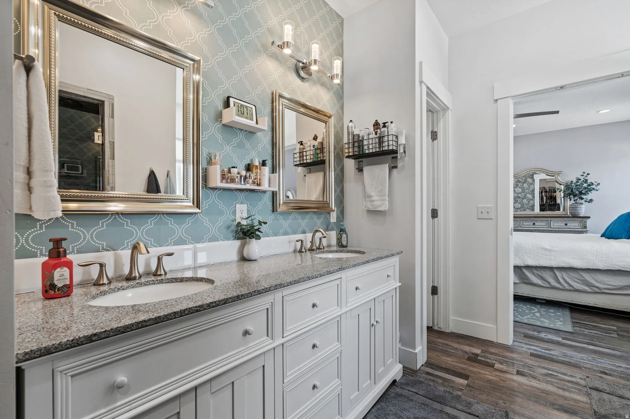 Ensuite bathroom featuring double vanity and dark wood-style floors