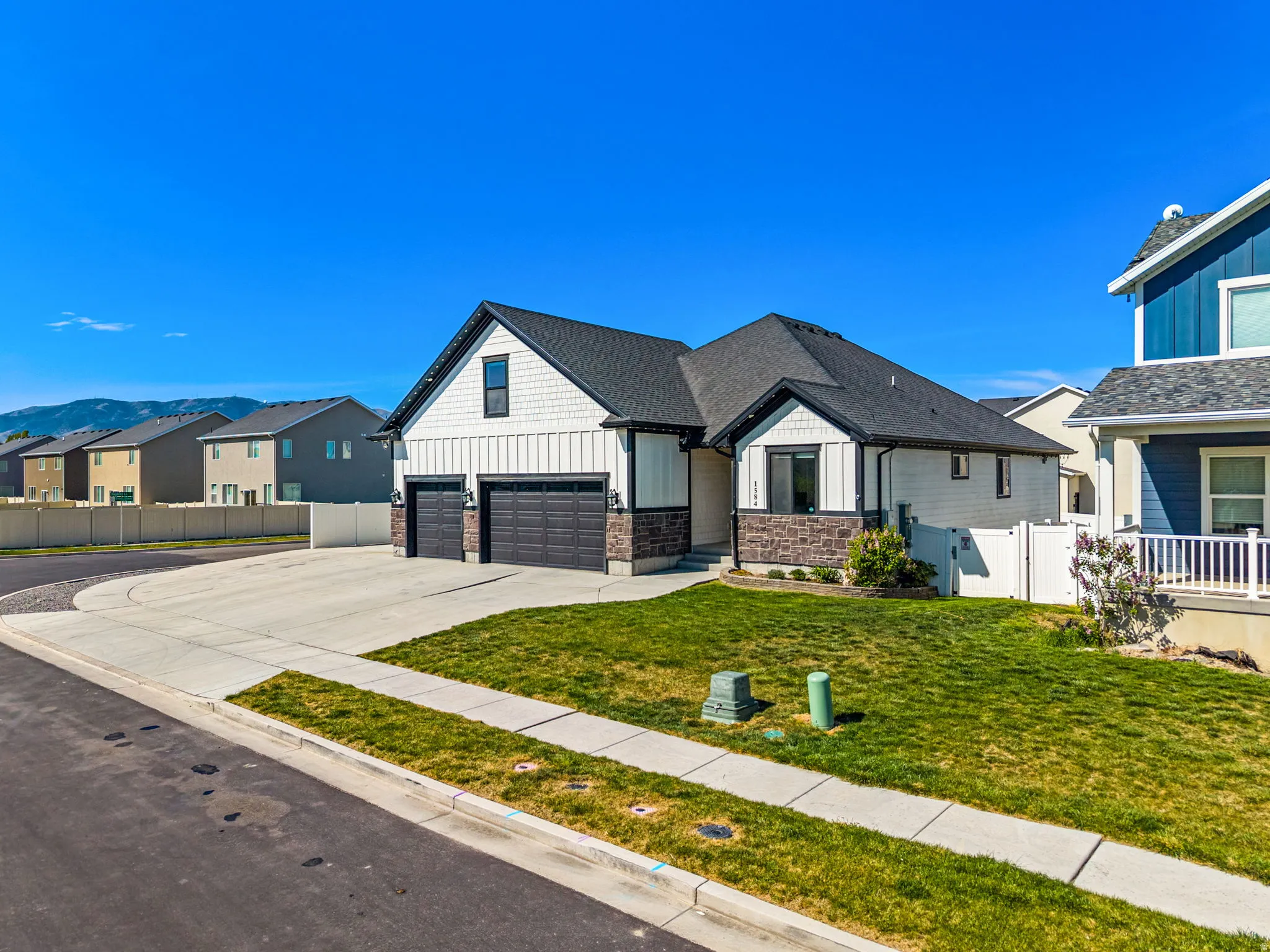View of front of house with board and batten siding, driveway, a residential view, stone siding, and an attached garage