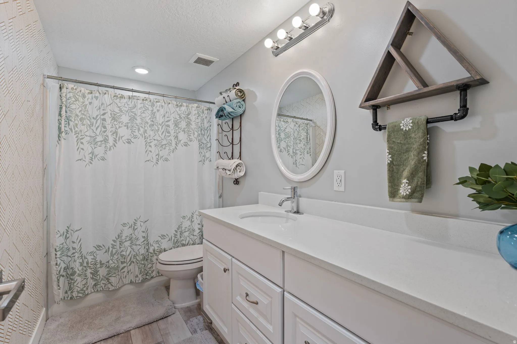 Full bathroom featuring vanity, light wood-style floors, shower / tub combo with curtain, and a textured ceiling