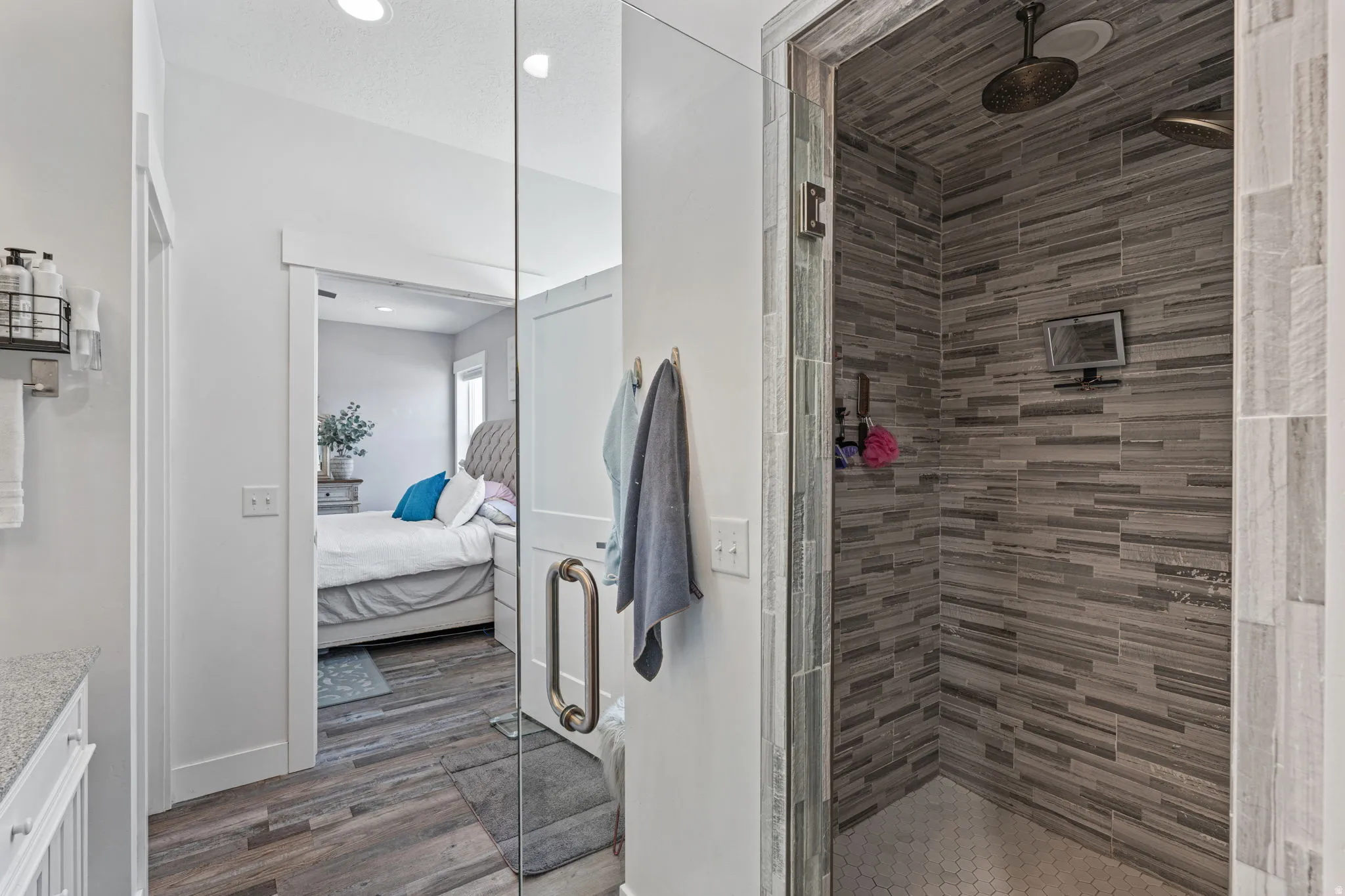 Ensuite bathroom featuring vanity, a stall shower, and dark wood-type flooring