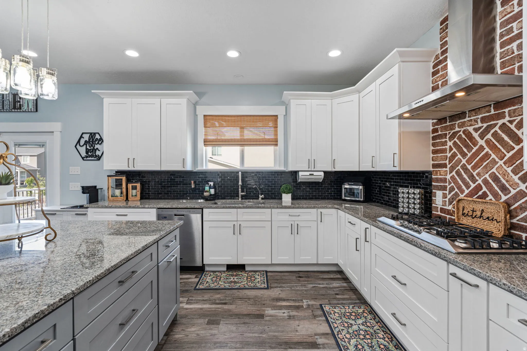 Kitchen featuring two tone cabinets, light stone countertops, stainless steel appliances, dark wood-style flooring, and decorative backsplash