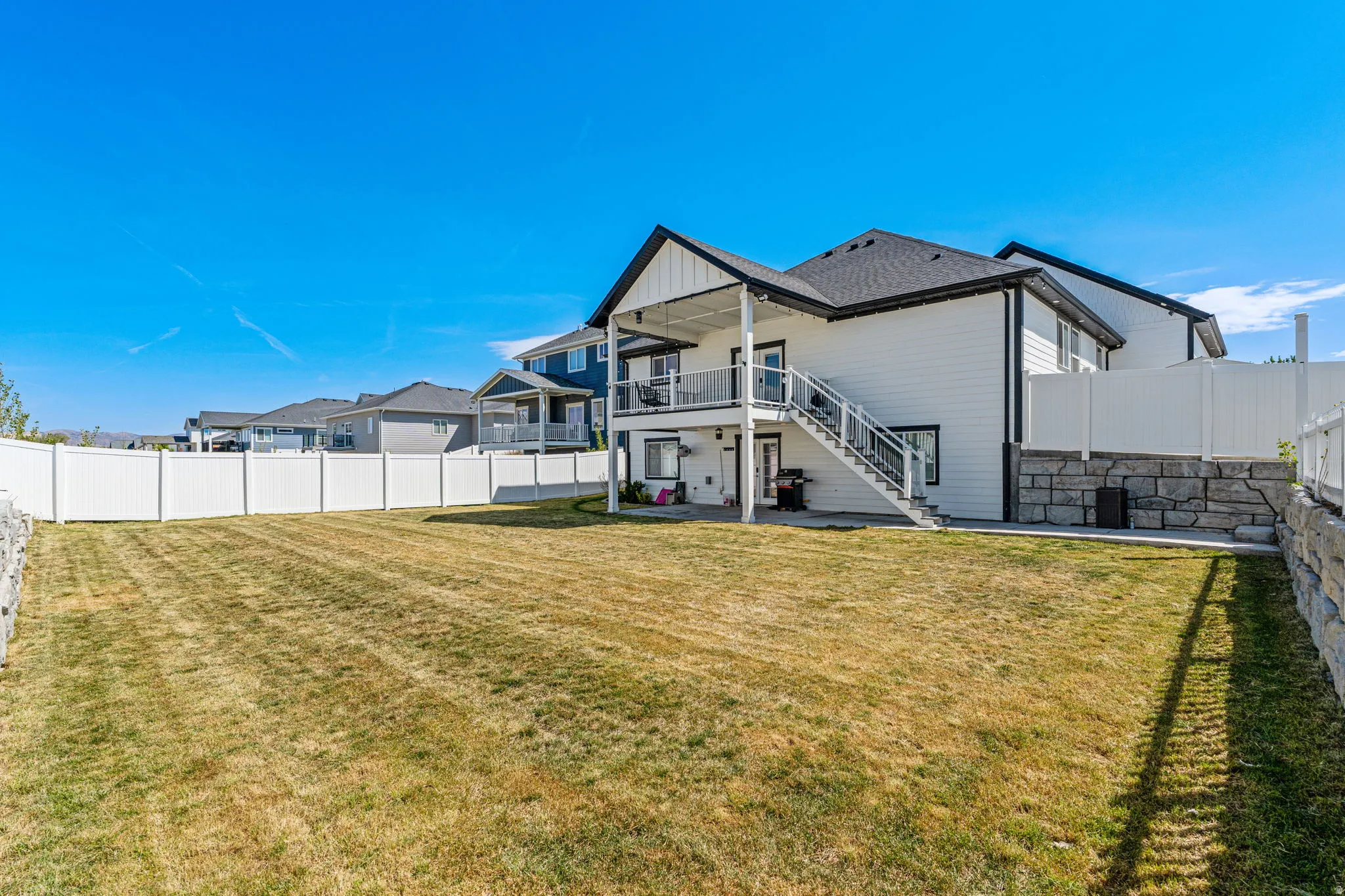 Rear view of house with a patio, a fenced backyard, and board and batten siding