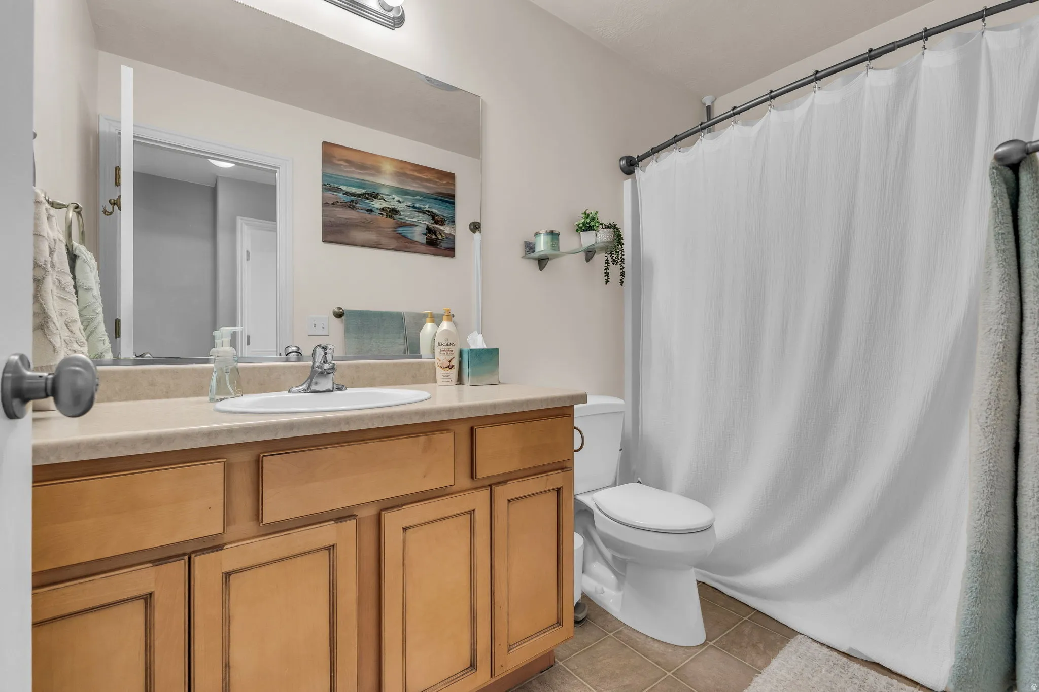 Full bathroom featuring vanity, light tile patterned floors, and curtained shower