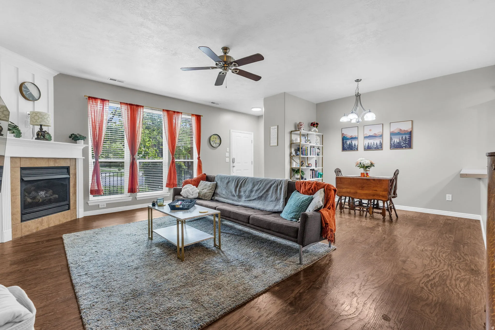 Living area with a fireplace, ceiling fan, dark wood finished floors, and a chandelier